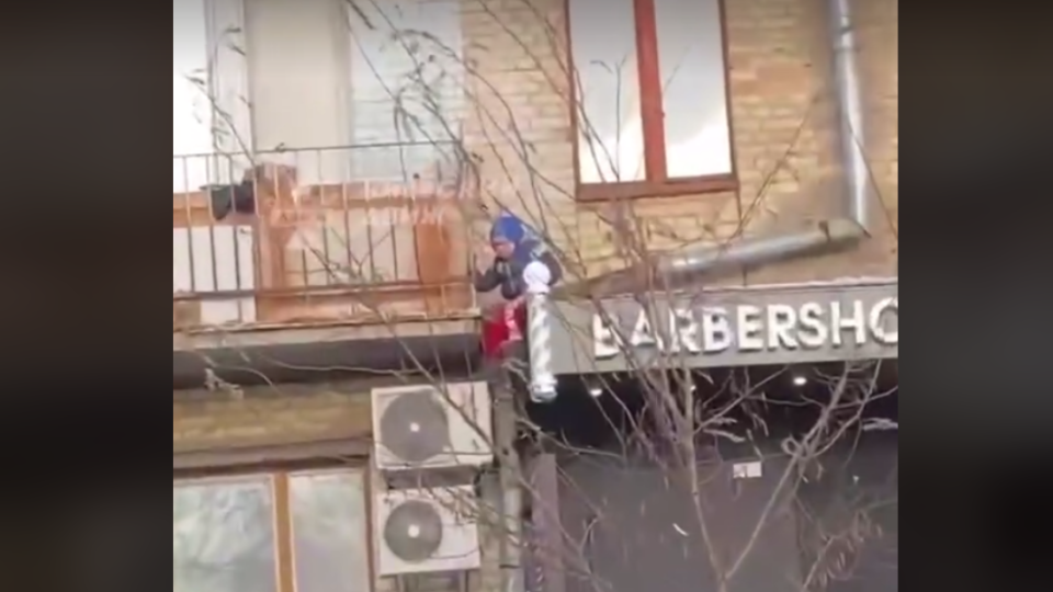 Хотів спуститися через балкон до мами: у Києві хлопчик застряг на піддашку магазину, відео